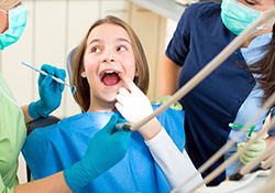 child in dental chair pointing to tooth